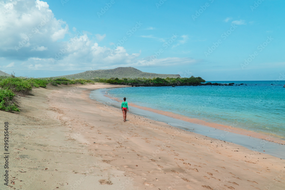 Woman walking on Galapagos beach. Tourist walking along Tropical beach with turquoise ocean waves and white sand. Sand bay view. Holiday, vacation, paradise, summer vibes. Shot in Isabela, San Crist