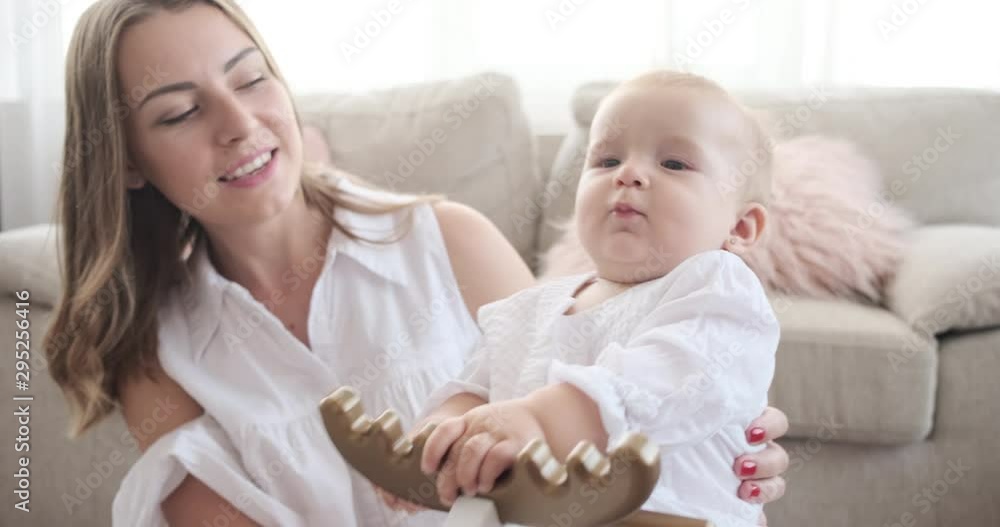 Happy mother with baby daughter on rocking deer toy at home Happy mother with baby daughter on rocking deer toy at home