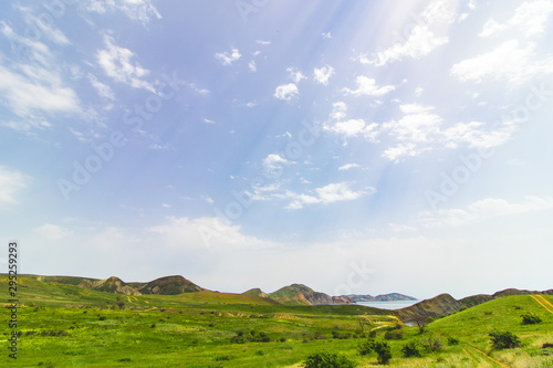 Sunny weather over a field with hills near the sea © Дмитрий Горелкин