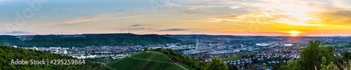 Germany, XXL panorama view over beautiful downtown of stuttgart city in neckar valley between green mountains in warm orange sunset mood
