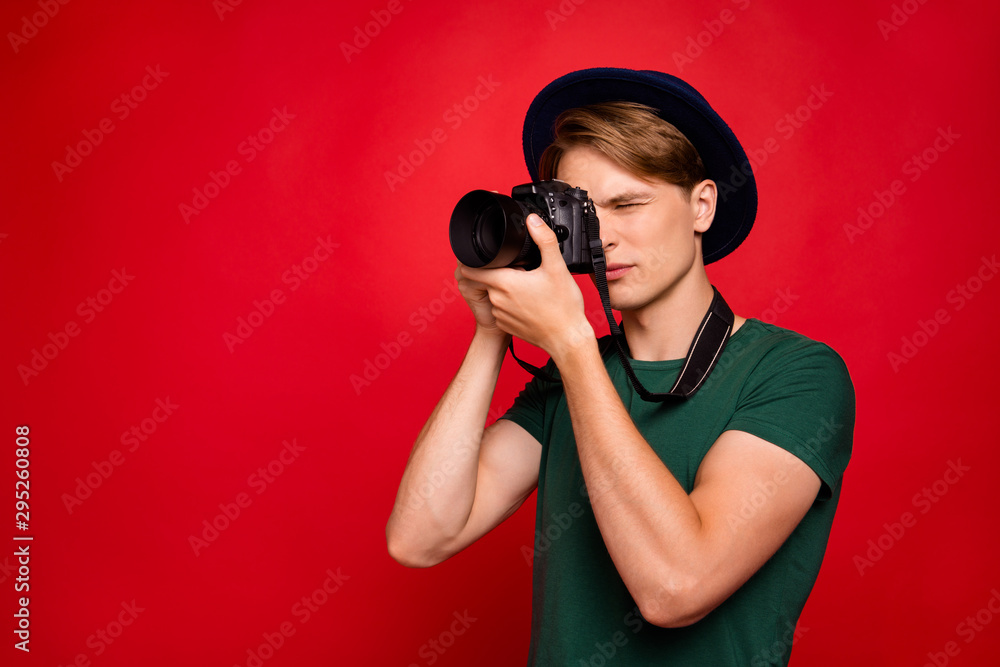 Obraz premium Profile side photo of concentrated guy have tour voyage abroad want shoot picture photo on his digital camera wear blue stylish trendy green t-shirt isolated over red color background