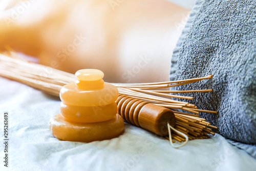 Massage accessories. Stone yellow jade and bamboo beaters for massage on the background of recumbent girls.