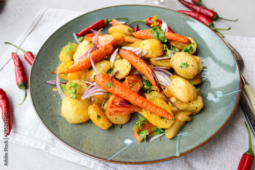warm salad of baked potatoes and carrots with red onions, spices and tomatoes