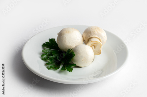 Heap of champignons on plate isolated on white background. Sliced mushrooms top view