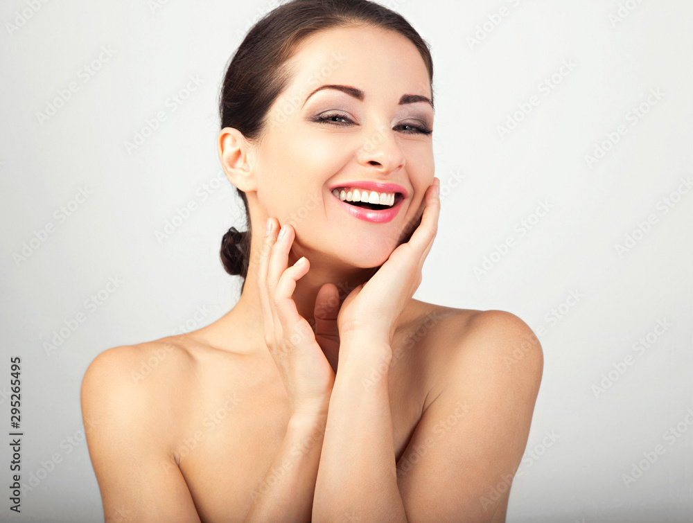 Beautiful woman touching herself face skin. Smiling laughing female model applying skincare moisturizer on the face. Beauty and anti aging treatment. Beautiful woman touching herself face skin. Smiling laughing female model applying skincare moisturizer on the face. Beauty and anti aging treatment.