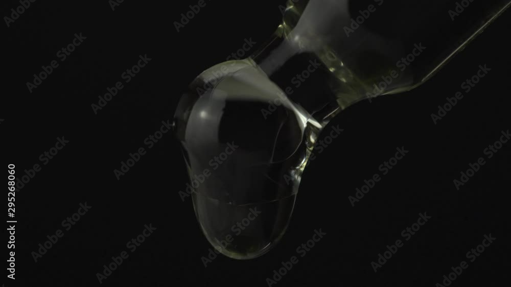 Liquid cosmetic oil dropping from laboratory glass pipette dropper. Face and hands skin care concept. Sauna spa exotic therapy treatment for body. Liquid cosmetic oil dropping from laboratory glass pipette dropper. Face and hands skin care concept. Sauna spa exotic therapy treatment for body.