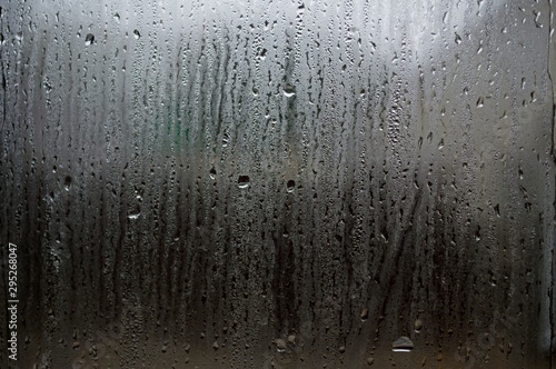 Fog and raindrops on window glass, dark background and lantern l