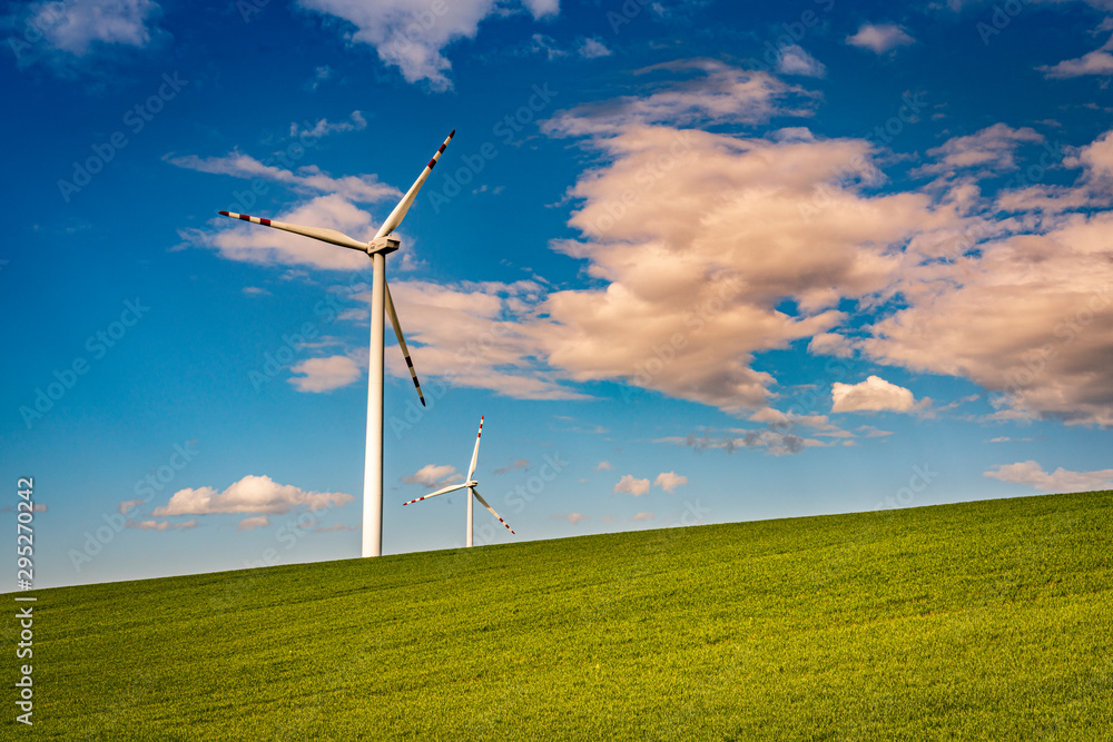 Obraz premium Wind turbines in the green field with blue sky and clouds