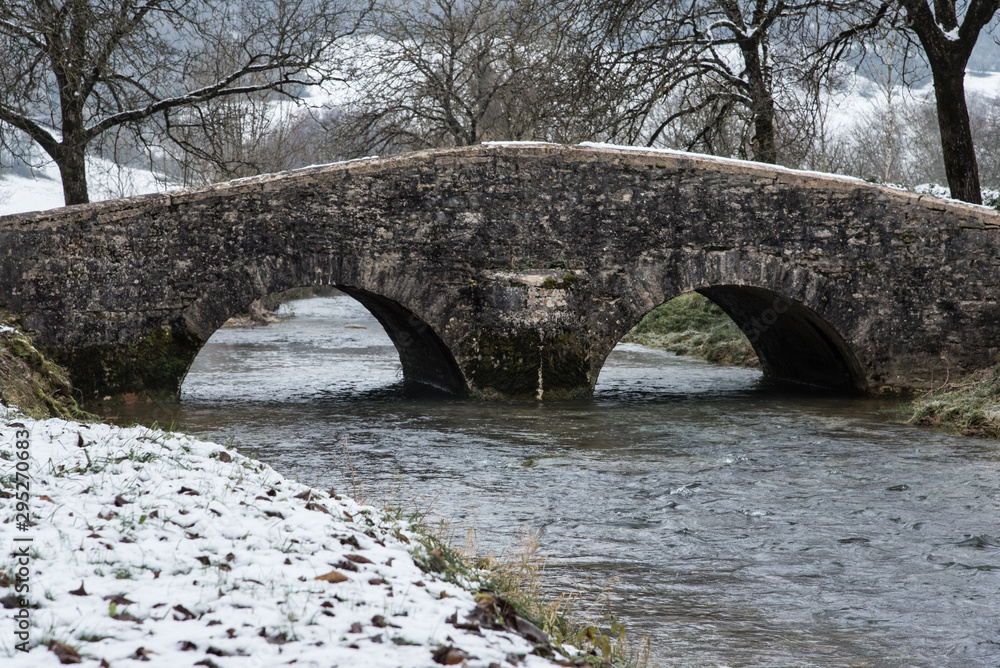 un vieux pont jura en pierre médiéval en hiver avec neige et rivière