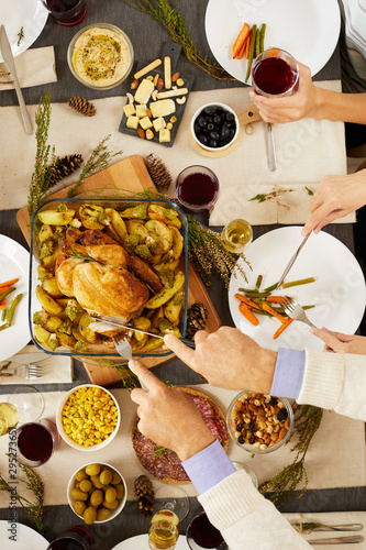 Close-up of man cutting roast turkey and is going to eat it at the table during holiday dinner