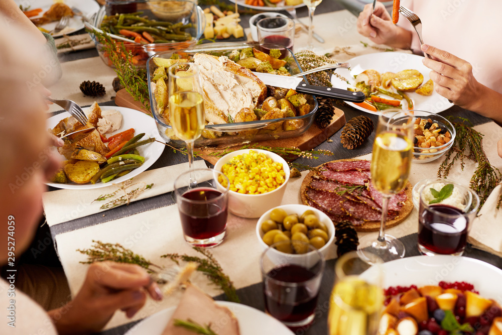 Close-up of family sitting at dining table and eating holiday dinner together Close-up of family sitting at dining table and eating holiday dinner together