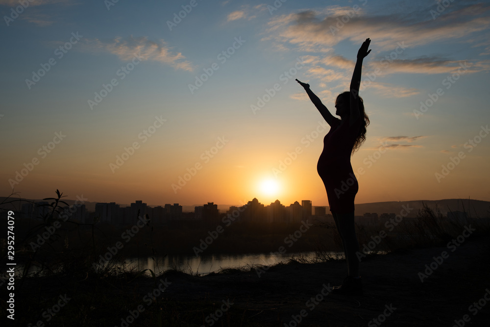 Silhouette of a happy pregnant girl on a background of a beautiful sunset in summer Silhouette of a happy pregnant girl on a background of a beautiful sunset in summer