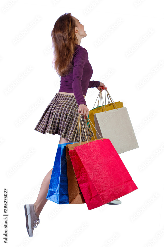 side view of a woman jumping with shopping bags.