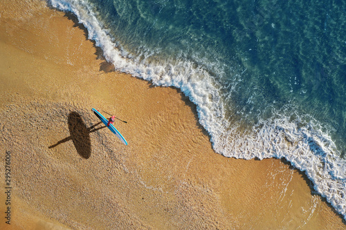 Surfer on beach with paddleboard. Aerial view. photo