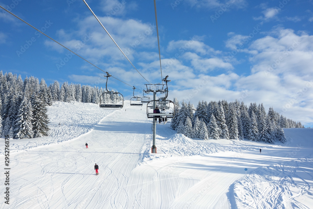 Wintersports fans riding the ski lift to empty pistes. Wintersports fans riding the ski lift to empty pistes.