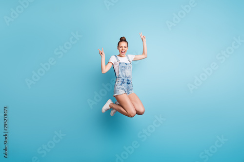 Full length body size photo of overjoyed enjoying nice cute girlfriend showing you v-sign while jumping being isolated with blue background