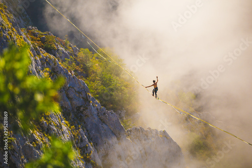 Fotografie, Obraz Highliner goes on a sling above the clouds.