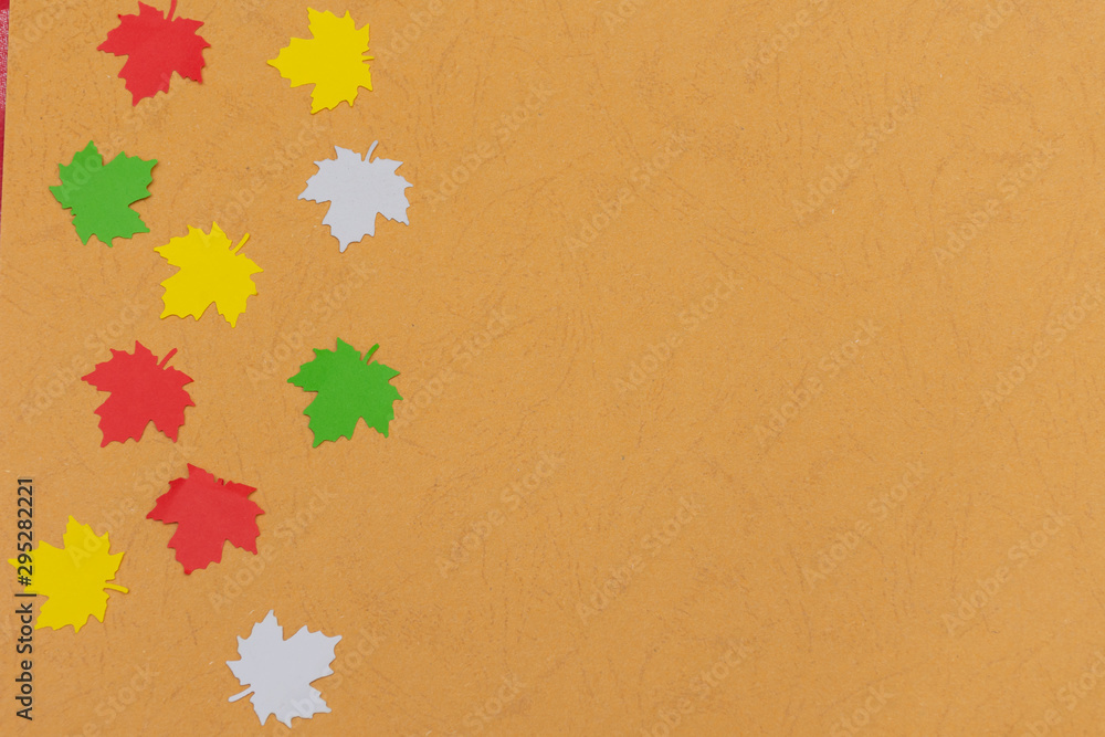 Warm fall seasonal orange flatlay with falling festive colorful maple leaves from side on open concept and copy space availability right. Warm fall seasonal orange flatlay with falling festive colorful maple leaves from side on open concept and copy space availability right.