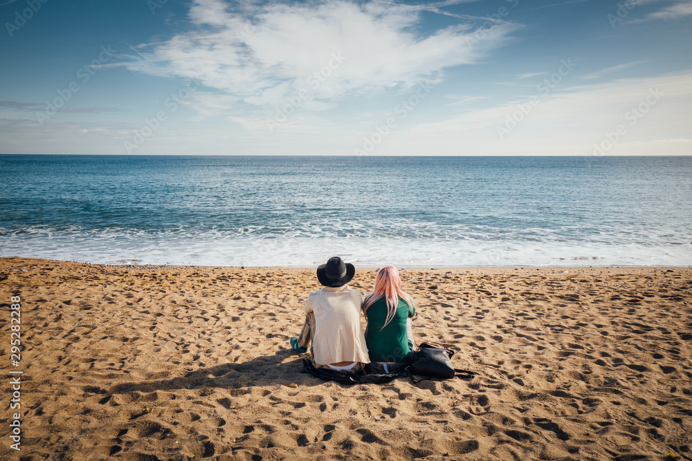 un couple assis sur la plage regarde la mer, les vagues et l'horizon pendant les vacances