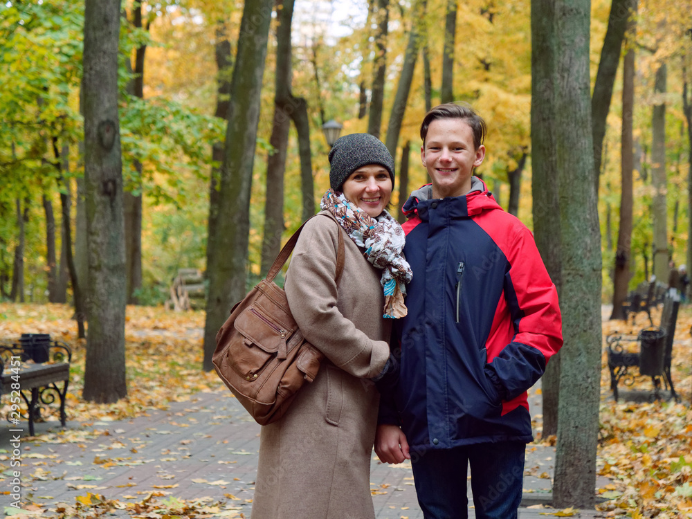 mother with her teenager son in autumn yellow park