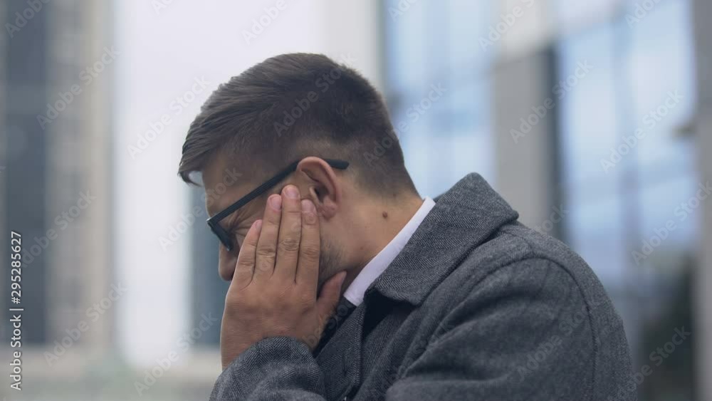 Man writhing in toothache outdoors, tooth and gum sensitivity, caries prevention Man writhing in toothache outdoors, tooth and gum sensitivity, caries prevention