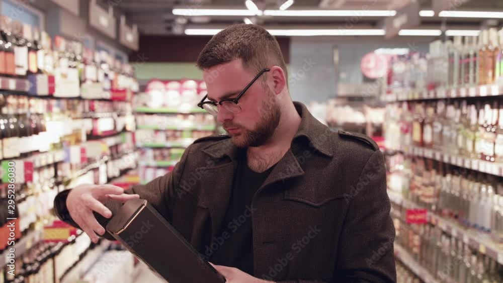 The man chooses the alcohol at market shelfs The man chooses the alcohol at market shelfs