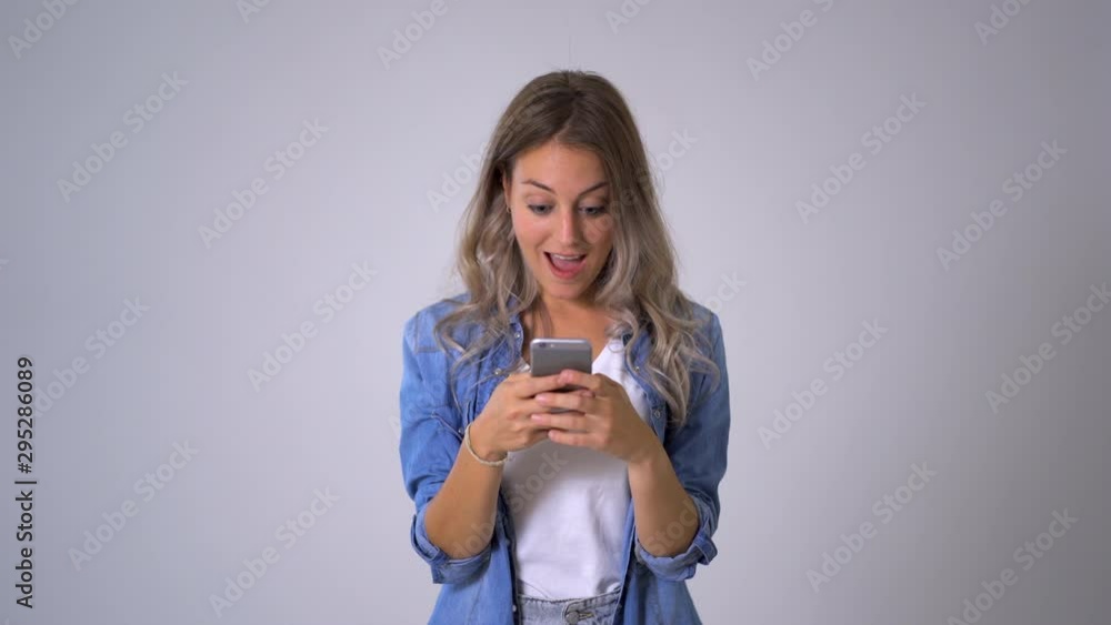 Beautiful blonde woman using smart phone posting on her blog in social media and happy with likes from followers and online business.Isolated on neutral background. In entrepreneur, online networking Beautiful blonde woman using smart phone posting on her blog in social media and happy with likes from followers and online business.Isolated on neutral background. In entrepreneur, online networking