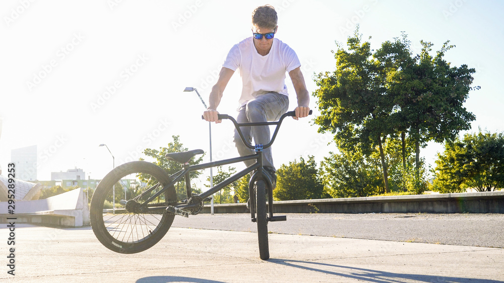 CLOSE UP Extreme bmx biker riding in sunny park stopping the bmx bike and  doing nollie tail whip trick on beautiful summer day foto de Stock | Adobe  Stock