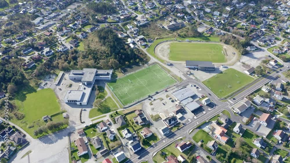 Aerial view above college football sports grounds in urban residential estate over rooftops birds eye view. Aerial view above college football sports grounds in urban residential estate over rooftops birds eye view.