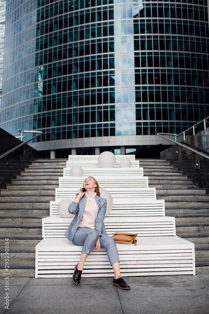 young happy business woman talking on the phone in the background of an office building