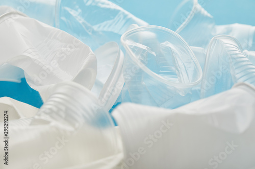 crumpled white and transparent plastic cups on blue background