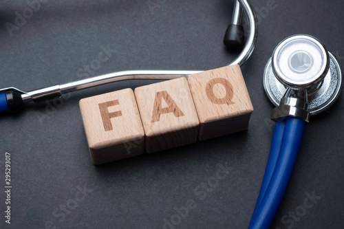 Wooden block form the word FAQ with stethoscope. Medical concept.