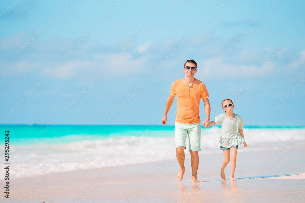 Little girl and happy dad having fun during beach vacation