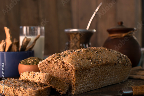 pan casero con semillas para desayuno sobre tabla de madera y fondo oscuro