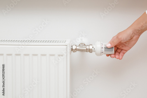 Obraz na plátne Woman hand adjusting temperature of radiator.