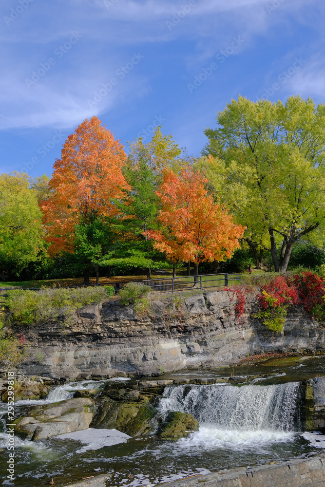 Vibrant orange, yellow, red and green fall colors on trees near waterfall