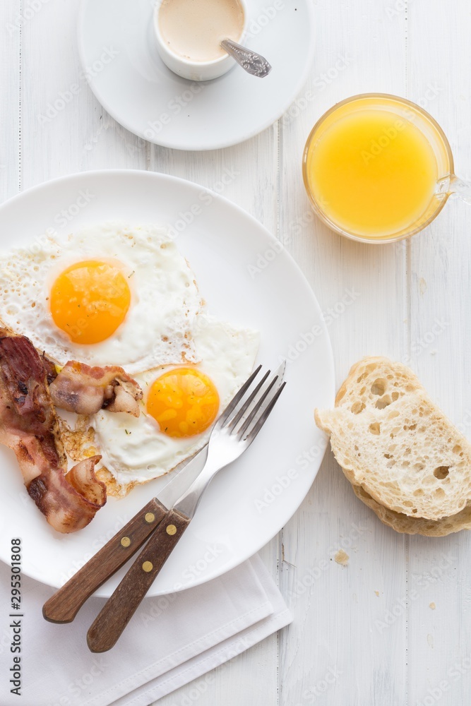 Full American Breakfast on white, top view, copy space. Sunny side fried eggs, roasted bacon Full American Breakfast on white, top view, copy space. Sunny side fried eggs, roasted bacon