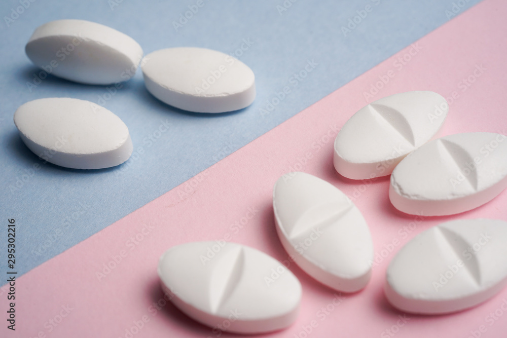 Top view of various white pills on blue and pink background Top view of various white pills on blue and pink background