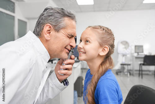 Girl opening widely eyes while oculist checking eyesight