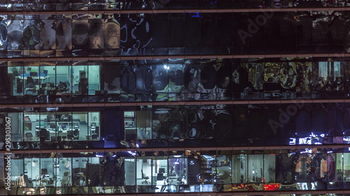 Office skyscraper exterior during late evening with interior lights on and people working inside night timelapse