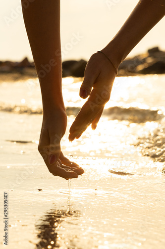 Hands of a girl touching the water on the beach