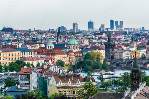 Aerial view of citycape of old town of Prague, with a lot of  rooftops, churches, and the landmark of Charles Bridge, and Vltava river.