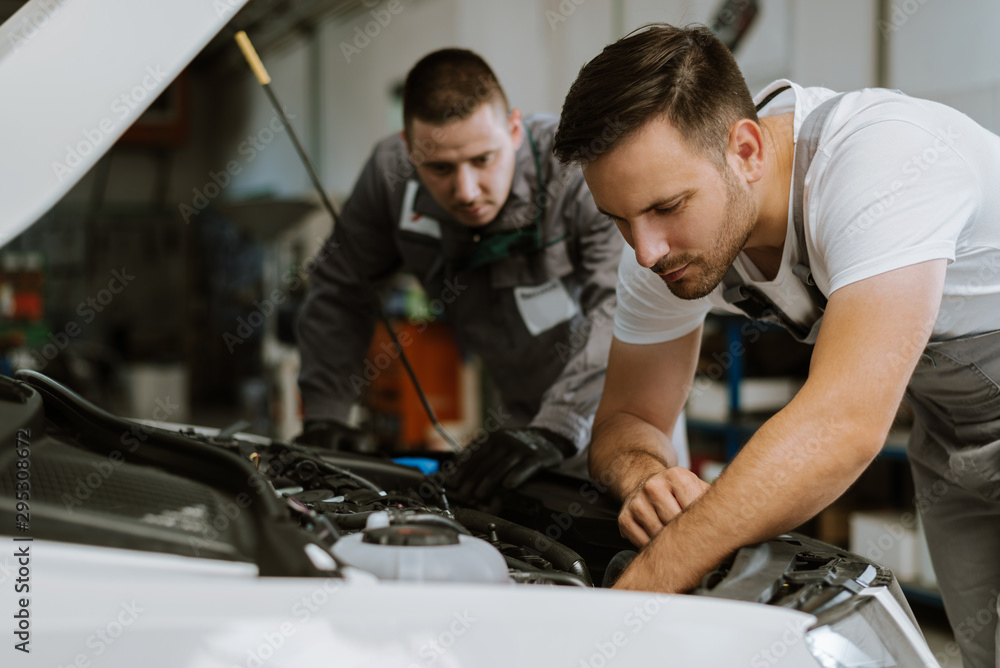 Auto mechanics working on car engine in a workshop Auto mechanics working on car engine in a workshop