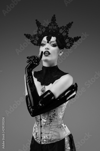Fotografie Portrait of a young woman wearing a lace cap, a corset and black latex gloves