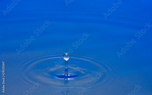 Water drops falling against the water surface splashing the background image