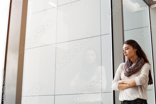 Standing young woman of looking at outdoors window 