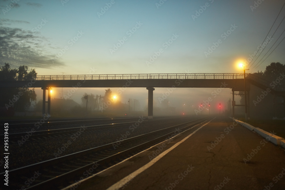 night railway is lit by yellow lanterns in the fog