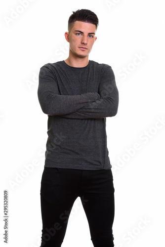 Studio shot of young handsome man standing with arms crossed