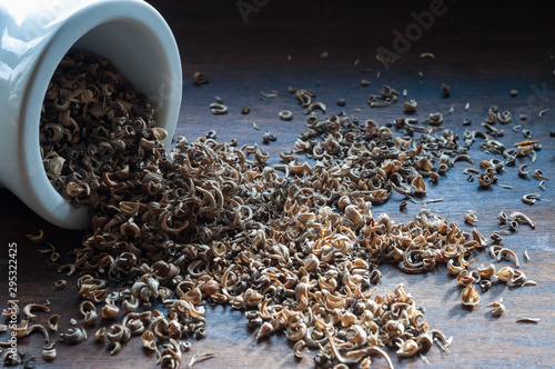marigold seeds in a white bowl, close-up on a wooden background
