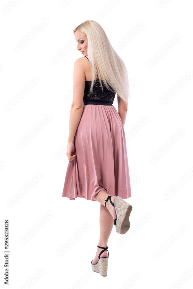 Blonde young beauty woman fashion model with smooth hair posing on one leg looking down. Back view. Full body isolated on white background. Blonde young beauty woman fashion model with smooth hair posing on one leg looking down. Back view. Full body isolated on white background.